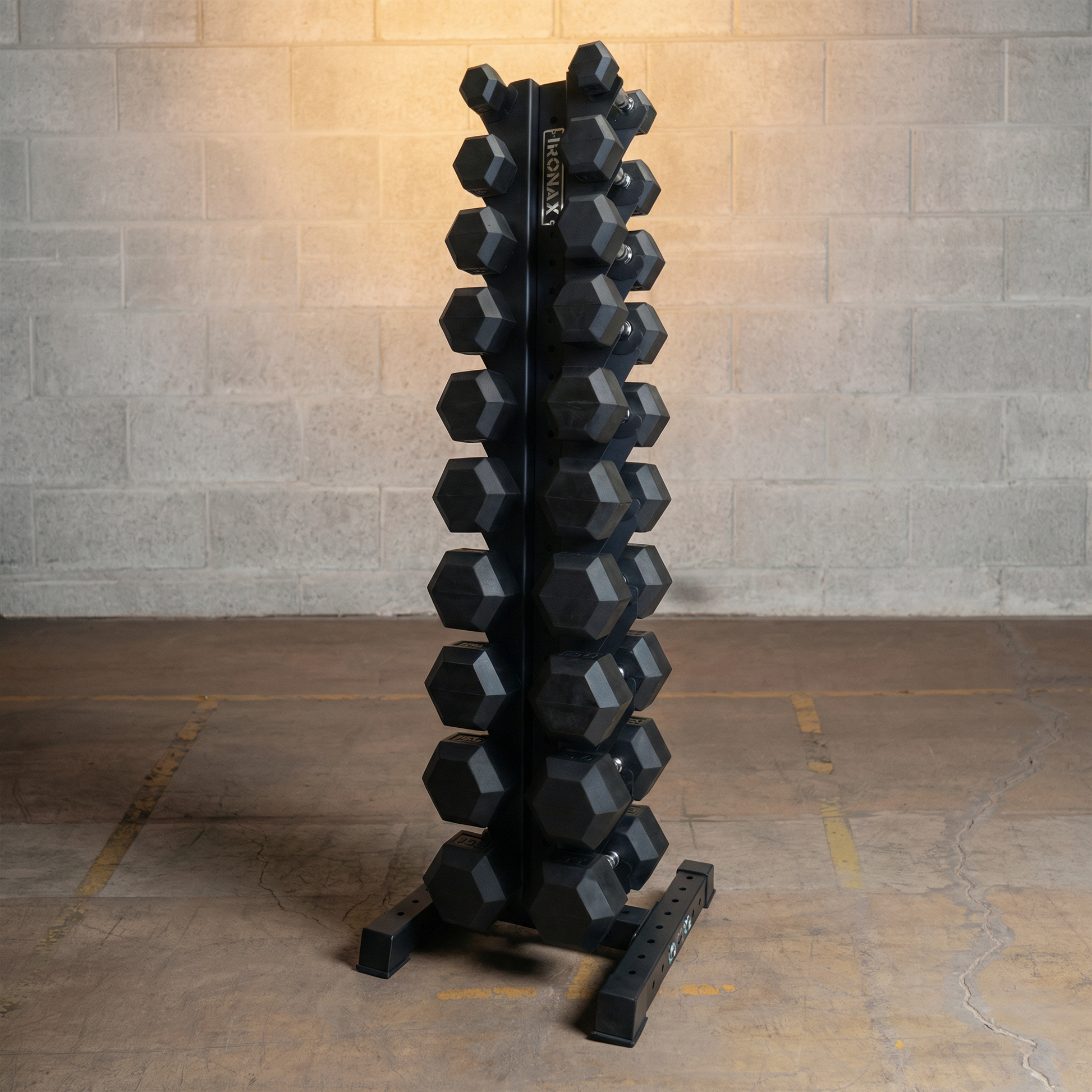 Set of black hexagonal dumbbells on a rack against a gray brick wall.